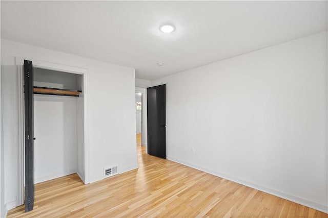 unfurnished bedroom featuring light wood-style floors, baseboards, and a closet