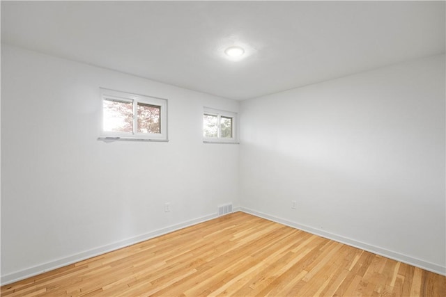 spare room featuring baseboards and light wood-style floors