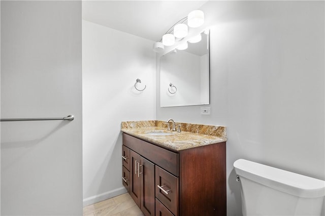 bathroom featuring vanity, toilet, and baseboards