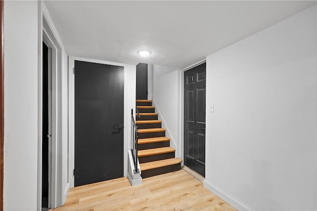 stairway with wood finished floors and baseboards
