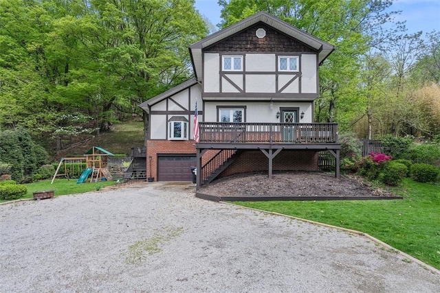 tudor house featuring dirt driveway, stairs, a garage, stucco siding, and a wooden deck