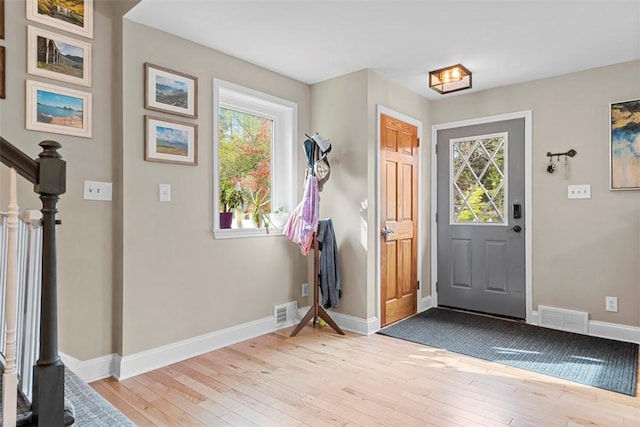 foyer featuring light wood-style floors, baseboards, and stairs