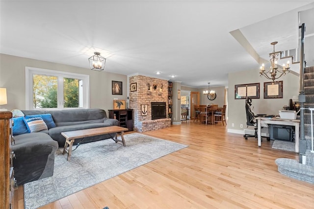 living area featuring a chandelier, light wood finished floors, a fireplace, and baseboards