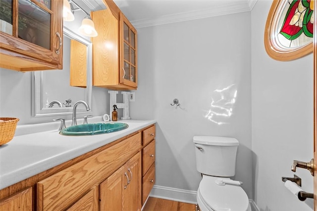 bathroom featuring ornamental molding, toilet, wood finished floors, vanity, and baseboards