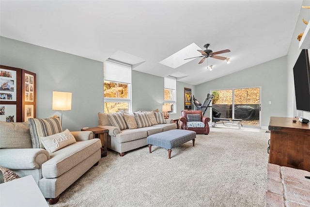 living area featuring a ceiling fan, carpet, a skylight, and vaulted ceiling