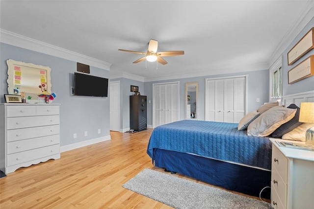bedroom with multiple closets, crown molding, light wood-type flooring, baseboards, and ceiling fan