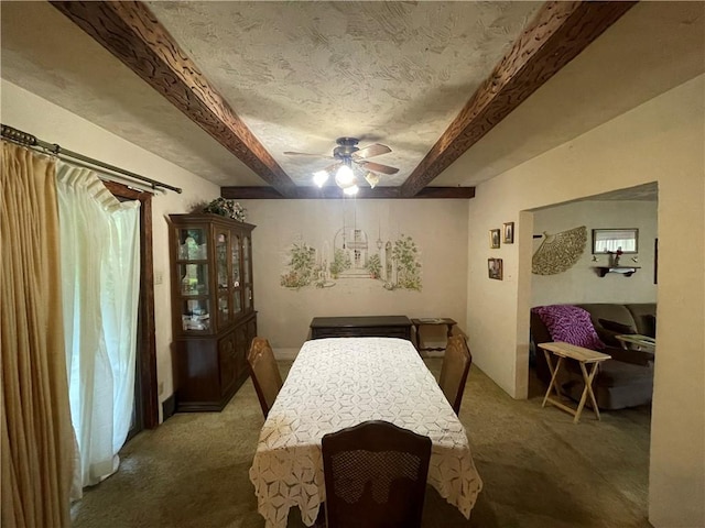 dining space featuring carpet floors, ceiling fan, beam ceiling, and a textured ceiling