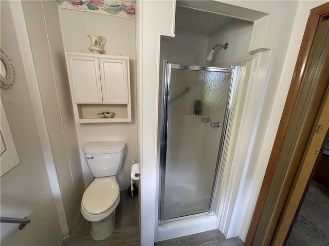 bathroom with a stall shower, toilet, and wood finished floors