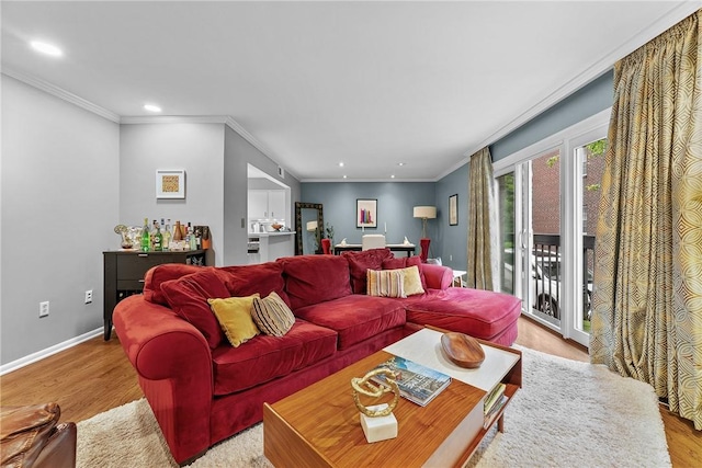 living room featuring light wood finished floors, recessed lighting, ornamental molding, and baseboards