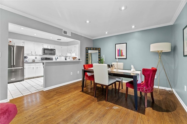 dining area with recessed lighting, crown molding, light wood-style flooring, and baseboards