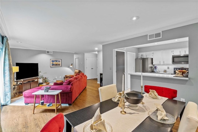 dining space with ornamental molding, light wood finished floors, and recessed lighting