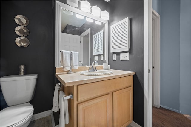 half bathroom with toilet, baseboards, and vanity