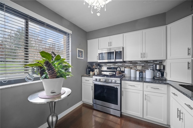 kitchen with appliances with stainless steel finishes, backsplash, white cabinets, baseboards, and dark wood finished floors