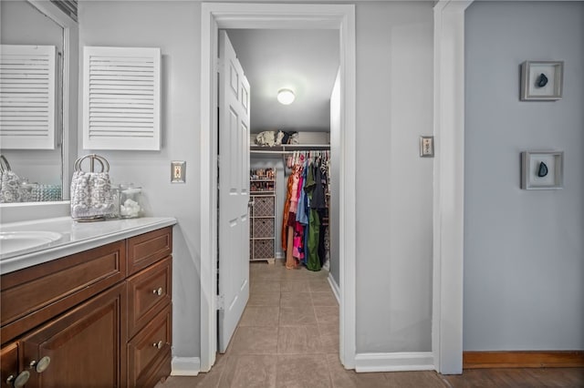 bathroom with baseboards, vanity, a spacious closet, and tile patterned floors