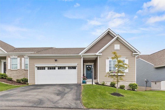 view of front facade with asphalt driveway, a garage, and a front lawn