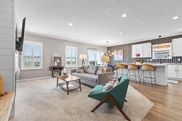 living room with baseboards, crown molding, recessed lighting, a textured ceiling, and light wood finished floors