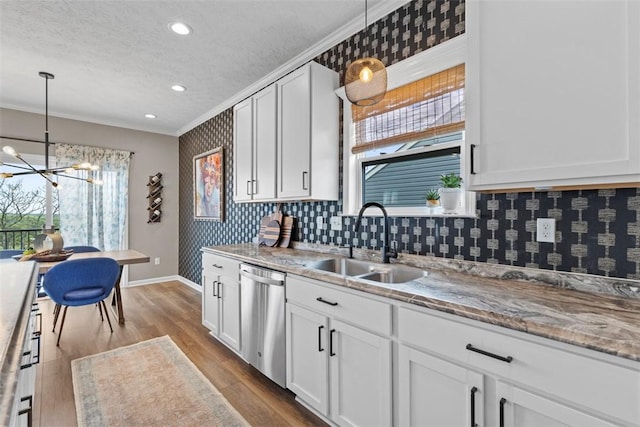 kitchen with stainless steel dishwasher, a sink, a chandelier, crown molding, and baseboards