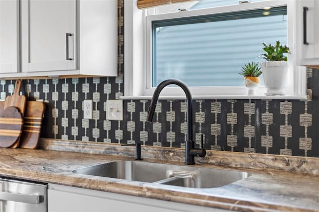 kitchen with a sink, dishwasher, and white cabinetry