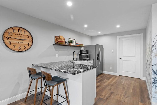 kitchen featuring open shelves, stainless steel appliances, a kitchen breakfast bar, dark wood finished floors, and baseboards