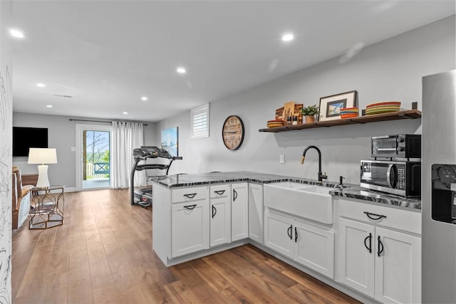 kitchen with open shelves, stainless steel appliances, a sink, recessed lighting, and dark stone countertops