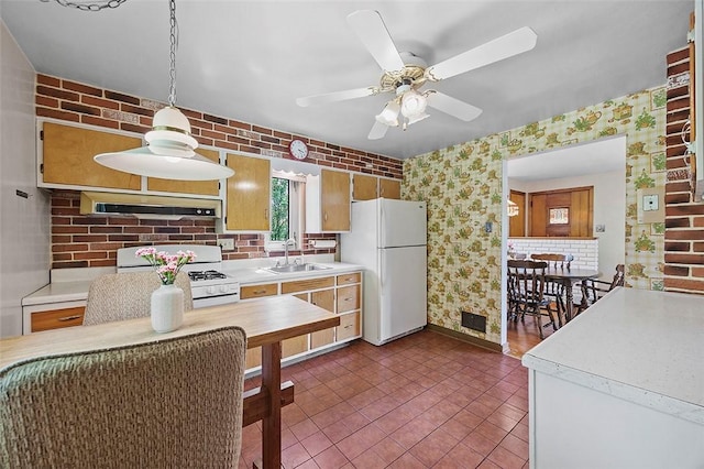 kitchen with white appliances, under cabinet range hood, wallpapered walls, a sink, and light countertops