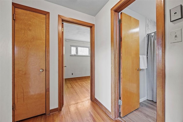 hall with light wood-type flooring and baseboards