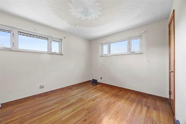 spare room featuring baseboards and light wood finished floors