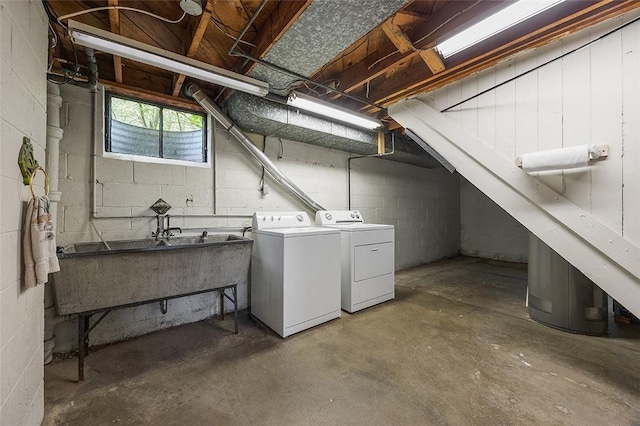 basement featuring washer and clothes dryer, concrete block wall, and a sink