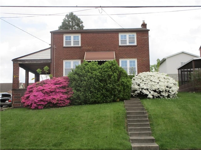 view of front of house with brick siding, a front yard, and a chimney
