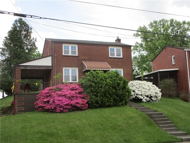 colonial-style house featuring brick siding, a front yard, and a chimney