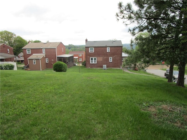 view of green lawn with a sunroom and a residential view