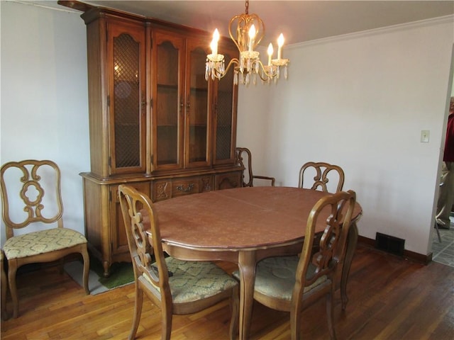 dining space featuring crown molding, wood finished floors, a chandelier, and baseboards