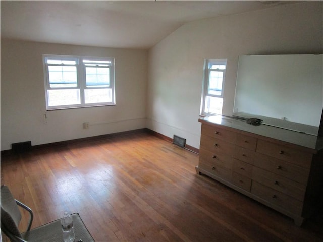 unfurnished bedroom featuring multiple windows, lofted ceiling, wood finished floors, and baseboards