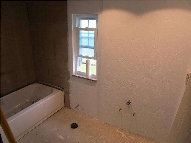 full bathroom featuring a textured wall and a tub