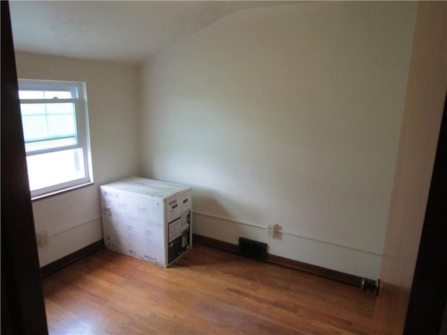unfurnished bedroom featuring light wood-style flooring and lofted ceiling