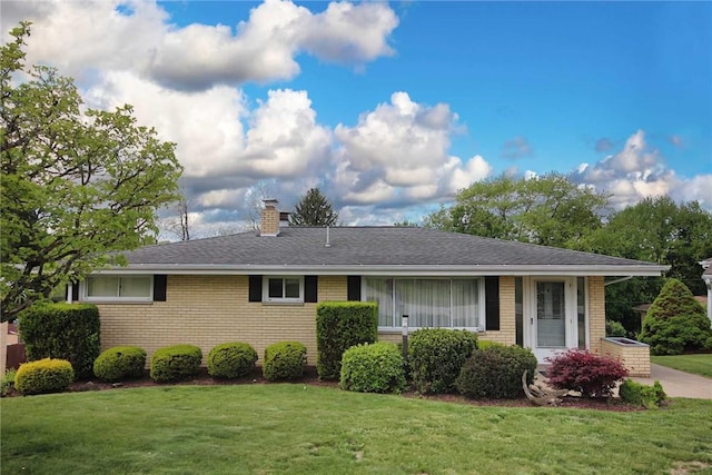 single story home featuring brick siding, a front lawn, a chimney, and a shingled roof