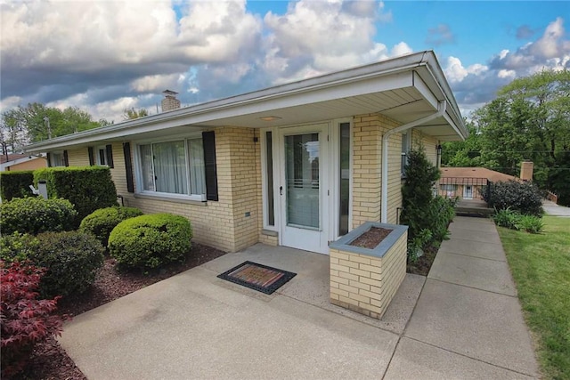 property entrance featuring brick siding and a chimney