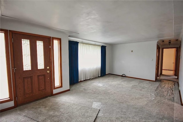 foyer entrance featuring carpet floors and baseboards