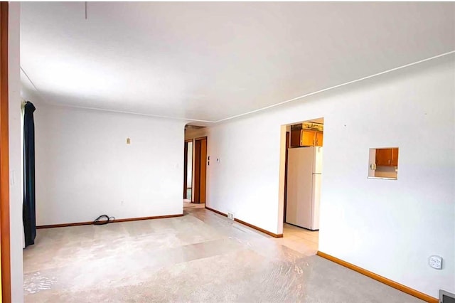 unfurnished room with light colored carpet and baseboards