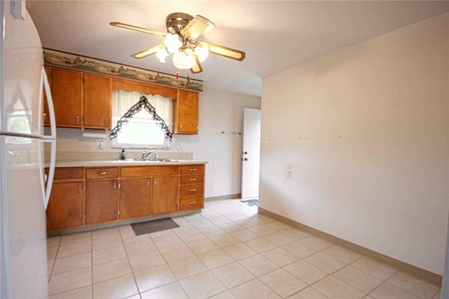 kitchen featuring freestanding refrigerator, brown cabinets, light countertops, and ceiling fan