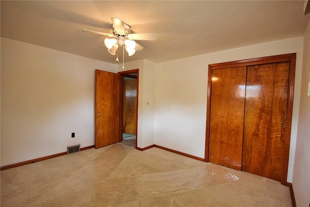 unfurnished bedroom featuring light colored carpet, baseboards, a closet, and a ceiling fan