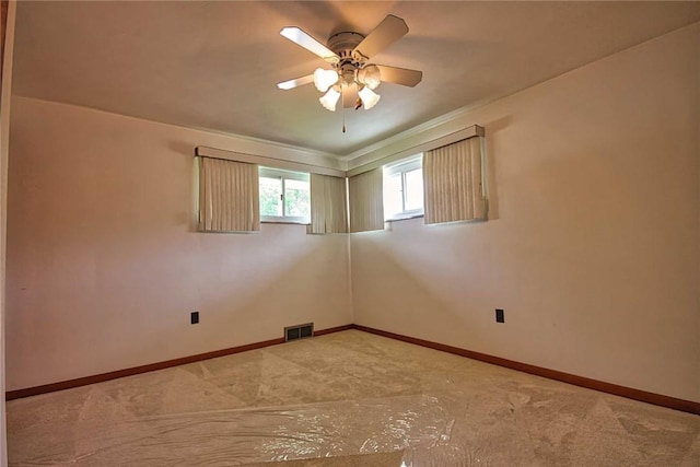 carpeted empty room featuring a ceiling fan, baseboards, and crown molding
