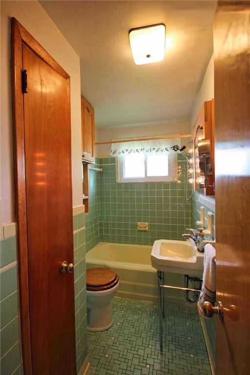 full bathroom with toilet, a sink, tile walls, tub / shower combination, and tile patterned floors