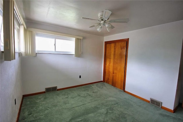 carpeted spare room with ceiling fan and baseboards