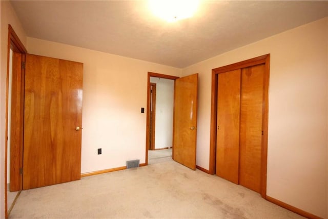 unfurnished bedroom featuring light carpet, a closet, and baseboards