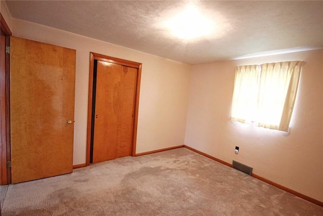 unfurnished bedroom with carpet, a closet, and baseboards