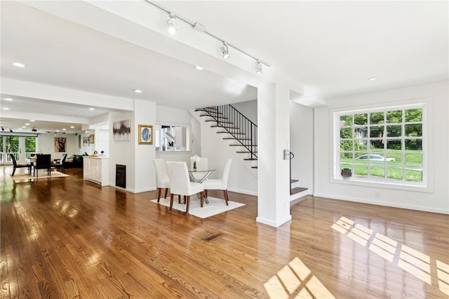 living room featuring stairway, wood finished floors, baseboards, recessed lighting, and rail lighting