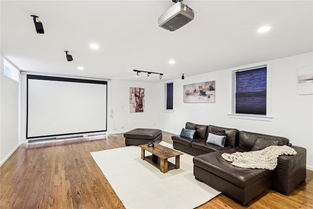 home theater room with wood finished floors, recessed lighting, baseboards, and rail lighting