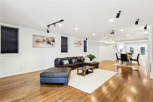 living room featuring wood finished floors, track lighting, recessed lighting, and baseboards