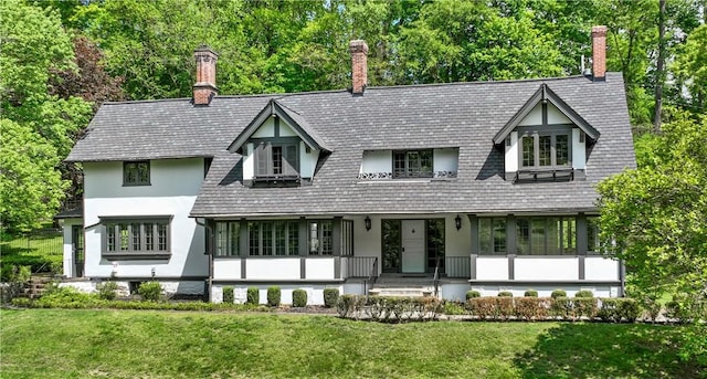 view of front of property with a front lawn, stucco siding, and a chimney